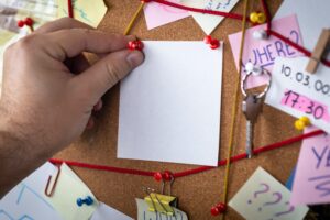 Hand pinning a reminder to a cork board